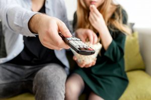 Photo of couple on a couch, watching a movie.